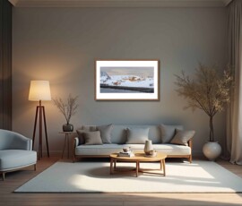 Fine-art photography print titled Arctic winter Sarnesfjorden I by Eva Eidsheim Photography. Showing a color cultural landscape of a tiny coastal settlement in Nordkapp on an icy winter day. Waves crash against the shore of a snow-covered landscape under a dark sky, capturing a raw Arctic atmosphere, printed on premium Hahnemühle art paper.